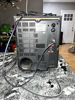 Rear view of receiver showing ventilation, control knobs, and speaker wire connectors with attached cords.