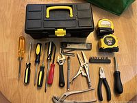 Top view of hand tools and tape measures arranged in front of closed toolbox.
