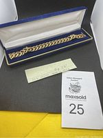 Bracelet displayed in blue velvet-lined box with handwritten note and auction tag visible