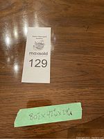 Top view of the oval dining table surface showing surface condition and dimension note with lot number card on table.