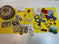 Overview of vintage pierced earrings collection with butterfly-themed storage box on yellow background