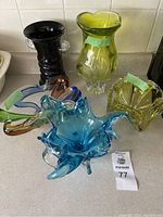 Overall view of the 5 heavy vintage glass pieces on a kitchen counter showing various shapes and colors.