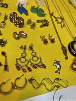 Photo showing a variety of vintage earrings and part of necklaces on a yellow background.