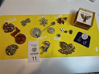 Full overview of all vintage brooches and pins on yellow fabric