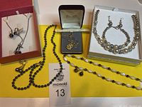 Photo showing five sets of jewelry including necklaces, bracelets, and earrings arranged on a table.