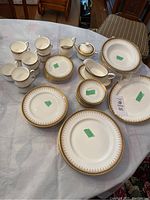 Image showing cups, cream and sugar set, gravy boat, some plates including soup bowls and dinner plates, arranged on a round table.