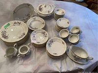 Full view of set arranged on cloth surface showing multiple pieces with purple flowers