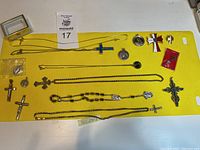 Top-down view of all religious jewelry items laid on yellow surface, showing crosses, chains, and medallions.