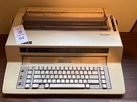 Front view of cream-colored Sharp ZX-370 electric typewriter with QWERTY keyboard.