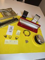 Overall lot laid out on yellow background showing rings, charm, bracelets, chains and storage cases