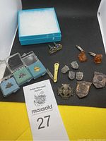 Photo of all pins, cufflinks, and assorted men's accessories arranged on black surface with auction tag 27