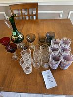 Full view of all 22 glassware items including glasses and decorative carafe on wooden table