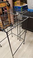 Three used metal plant stands with wire grid tops and slender legs, showing shoe scuff marks and general wear.