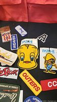 Photo showing a selection of colorful vintage patches including character and brand logos on a black surface with a red background.