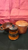 Three wooden items: decorative trinket container with a floral design, wooden bowl with handle, and round wooden box with lid, arranged together.