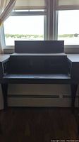 Front view of antique dark wood spinet writing desk showing central compartments and pull-out surface.