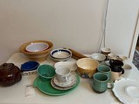 Overview of all ceramic and kitchen items including bowls, tea cup, teapot, egg cups, creamer, and rolling pin.