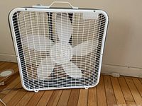 Front view of white Aerospeed box fan showing plastic grid and blades
