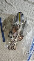 Various flatware pieces, cutlery of different sizes and handle patterns in plastic zip bags on fabric surface