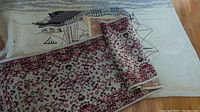 View of both rugs together, showing the rolled-up patterned runner on top of the nautical loop rug with ship design.