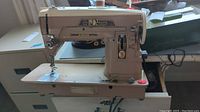 Full side view of Singer 403 Professional sewing machine with extended flat table and motor under base, beige metal body color.