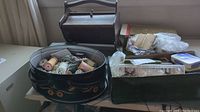 Antique wooden sewing box with handle, damaged top visible, surrounded by sewing supplies in tins and containers