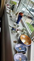 Wide shot of collection on windowsill including vases, cups, candles, and decorative items