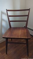 Front view of the solid cherry wood chair showing the slat-back design and seat shape.