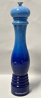 Front angled view of the tall blue Le Creuset pepper mill showing color gradient and shape
