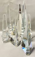 Photo showing all seven crystal obelisk bookends arranged in a group with good lighting to highlight facets and prismatic reflections.
