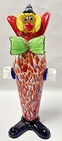 Front view of large Murano blown art glass clown figurine showing detailed facial features, colorful speckled body, green bow tie, and black shoes.