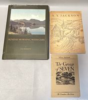 Photo showing all three books in the lot arranged side by side on a white surface: 'Sunday Morning with Cass' hardcover and two softcover books 'A.Y. Jackson Paintings 1902-1953' and 'The Group of Seven'