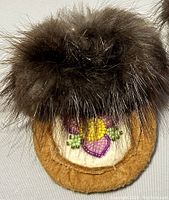 Close-up detail of one moccasin showing beadwork and fur trim