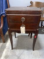 Front view of antique nightstand showing two drawers with brass ring pull handle and carved wood trim, scratches visible on surface.