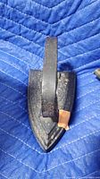 Photo of cast iron clothes iron showing the base and handle on blue quilted fabric.
