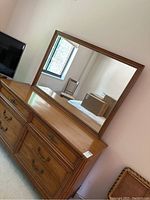 Full view of the dresser with mirror reflecting the room and window.