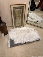 Photo of white faux fur area rug on carpet, showing texture and backing