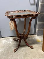 Photo showing the full side profile of the carved wooden pie table with glass inset top and tripod claw feet base.