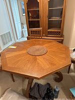 Octagonal oak dining table with visible polished wood grain and pedestal base with curved legs