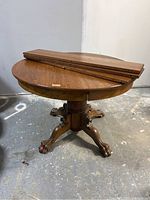 Full view of the round wooden dining table with three extension leaves placed on top.