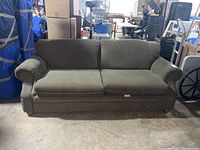 Full front view of green upholstered Simmons sofa showing rounded armrests, three seat cushions and wooden bun feet.