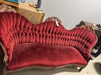 Front angle of the Victorian red velvet tufted sofa with carved wooden frame, shows condition and style