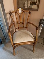 Front view showing the bamboo style frame and cream cushioned seat with floral embossing.