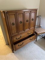 Front view of vintage walnut tall boy chest showing four cabinet doors and two open drawers.