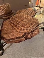 Set of six octagonal woven wicker placemats showing basket weave pattern in natural brown tones laid out on a glass table.