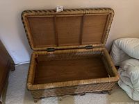 Open view of the wicker storage chest showing the wooden interior base and hinged lid.