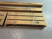 Stacked wooden slatted shelves wrapped in plastic, showing natural wood with knots.