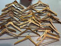 Lot of wooden clothes hangers displayed on a wall, showing multiple stacks of hanger types in natural and darker wood finishes.