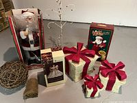 Overview photo of entire lot including large Santa figure, gift boxes, angel tree topper box, metal tree, burlap, and twig ball