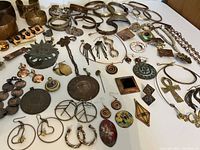 Wide angle photo showing a collection of copper and brass jewelry including bangles, necklaces, earrings, pendants, and brooches spread out on a table.